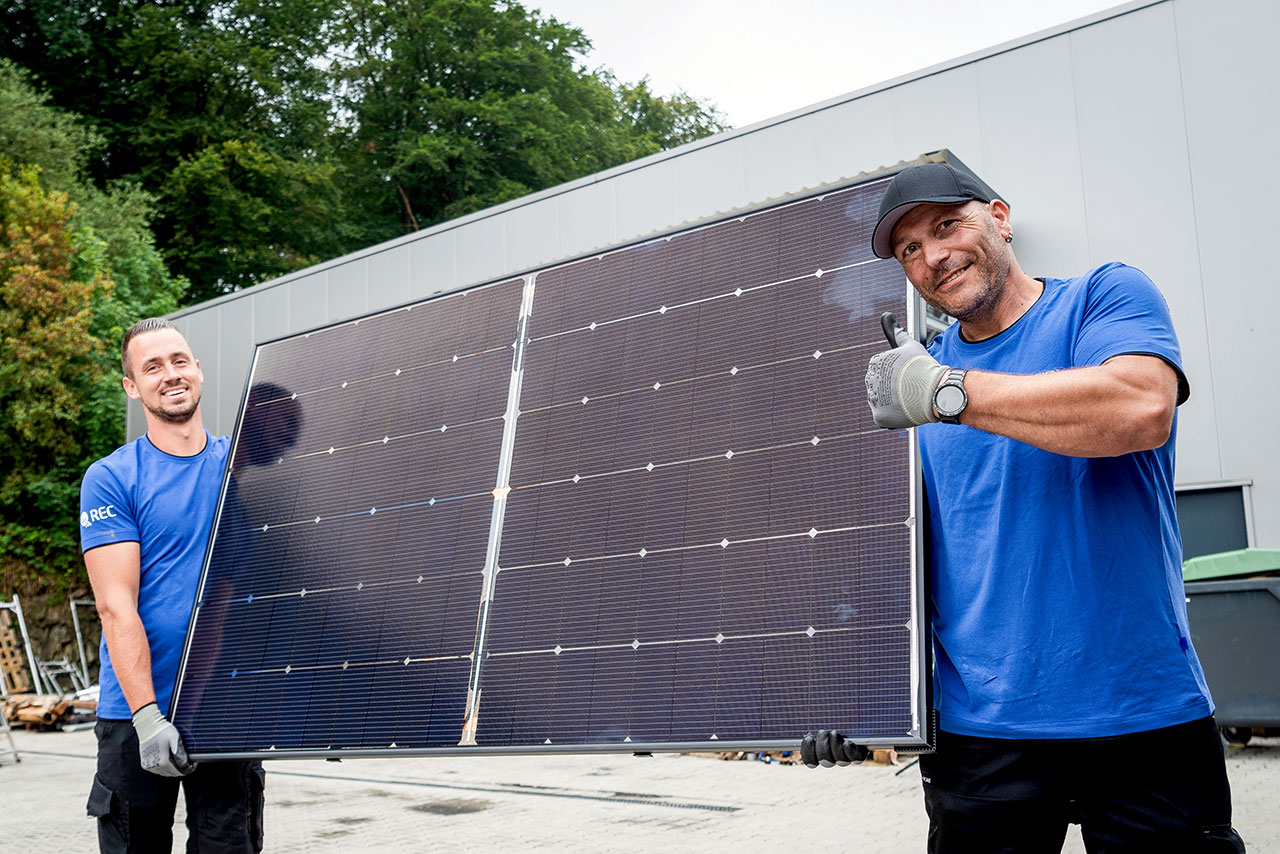 2 Hamacher Solar Handwerker mit einer Solarzelle in der Hand